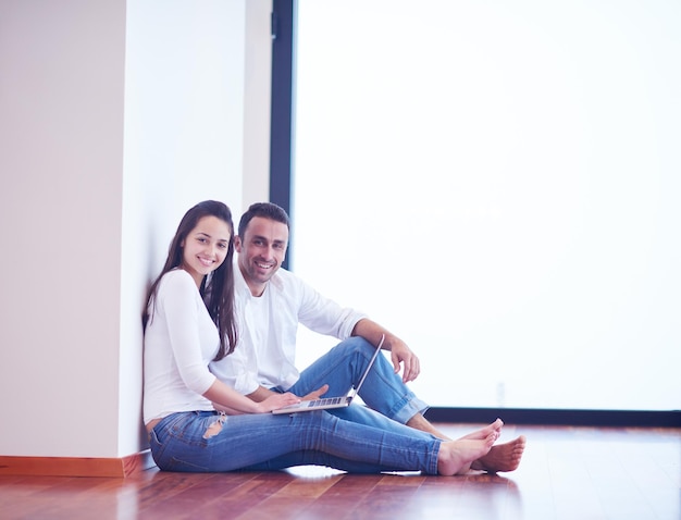 feliz pareja joven y relajada trabajando en una computadora portátil en el interior de una casa moderna