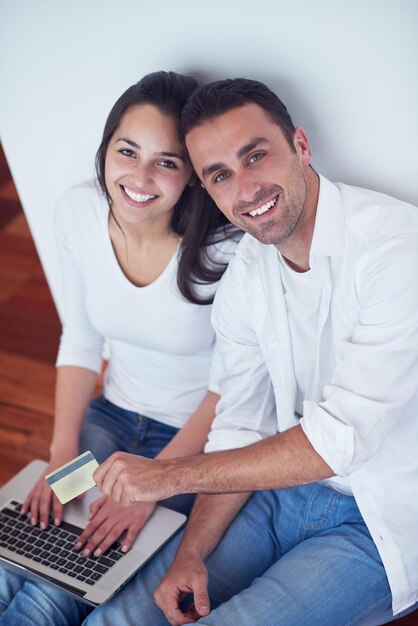 feliz pareja joven y relajada trabajando en una computadora portátil en el interior de una casa moderna