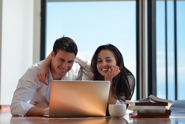 feliz pareja joven y relajada trabajando en una computadora portátil en el interior de una casa moderna