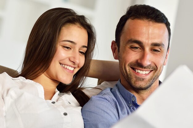 feliz pareja joven y relajada trabajando en una computadora portátil en el interior de una casa moderna