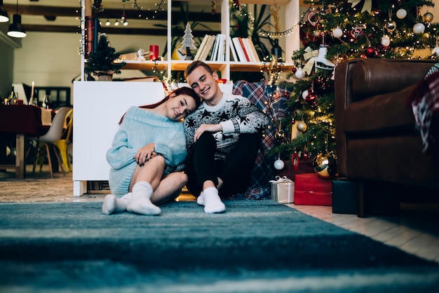 Feliz pareja joven relajándose en una casa decorada en Navidad