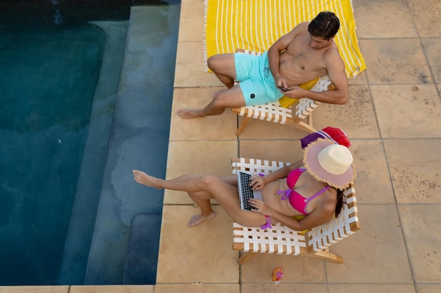 Feliz pareja joven relajándose cerca de la piscina