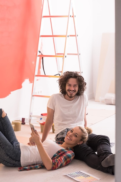 Feliz pareja joven relajándose después de pintar una habitación en su nueva casa en el suelo