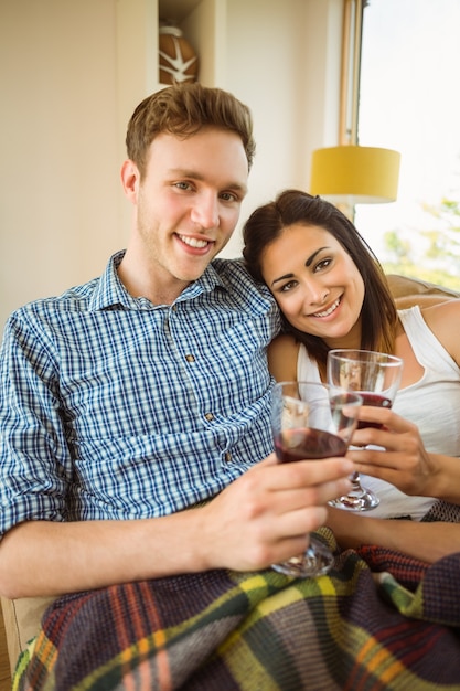 Feliz pareja joven relajante en el sofá con vino tinto