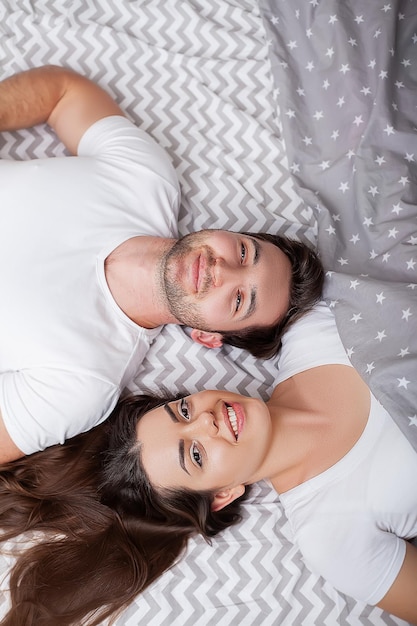 Feliz pareja joven sensual acostado en la cama juntos