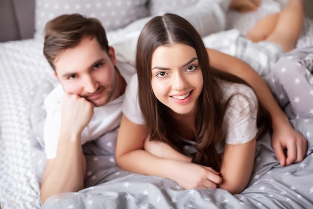 Feliz pareja joven sensual acostado en la cama juntos