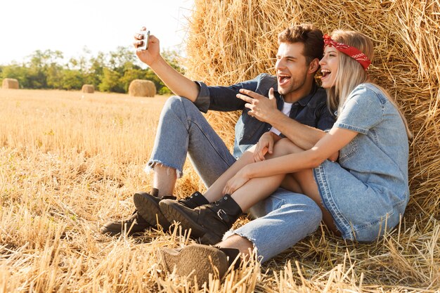 Feliz pareja joven sentada en el campo de trigo