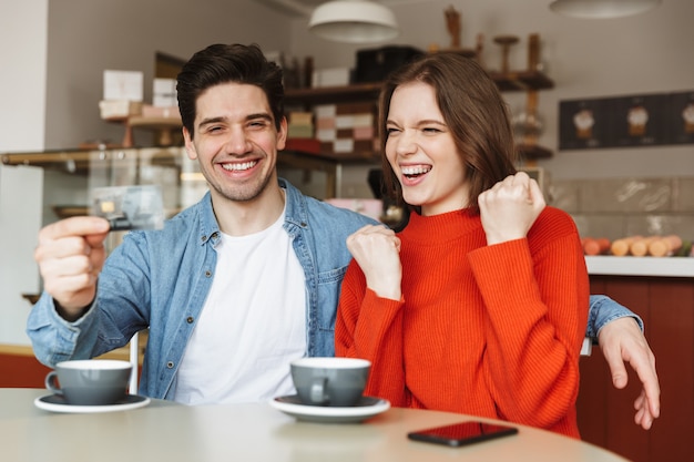 Feliz pareja joven sentada en la mesa de café