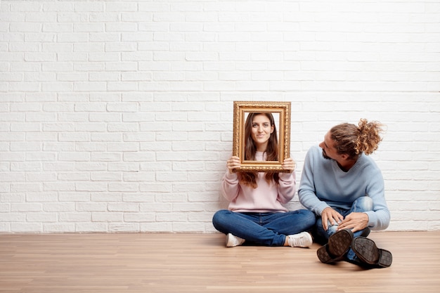 Feliz pareja joven sentada en el piso de su nueva casa. conc