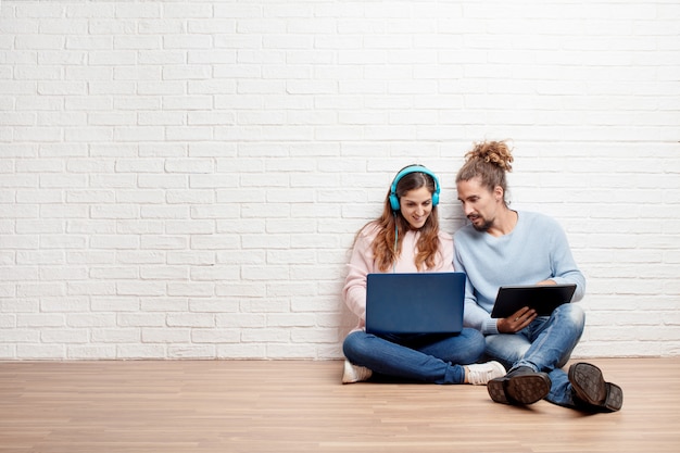 Feliz pareja joven sentada en el piso de su nueva casa con