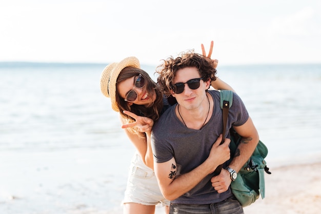 Foto feliz pareja joven sonriendo y divirtiéndose juntos en la playa