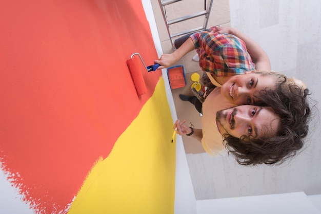 feliz pareja joven sonriente pintando la pared interior de la nueva casa