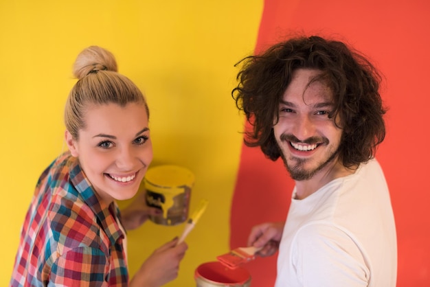 feliz pareja joven sonriente pintando la pared interior de la nueva casa