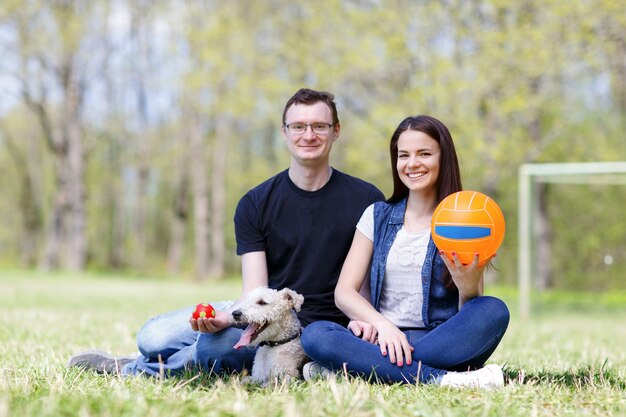 Feliz pareja joven y su perro en el parque