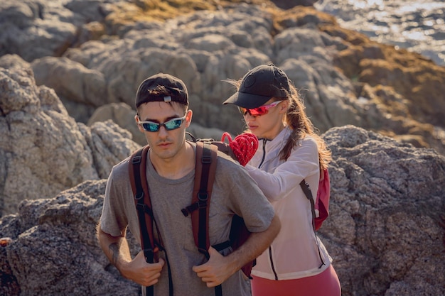 Feliz pareja joven sube a la cima de las montañas cerca del océano