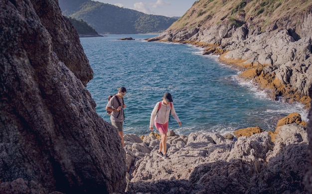 Feliz pareja joven sube a la cima de las montañas cerca del océano