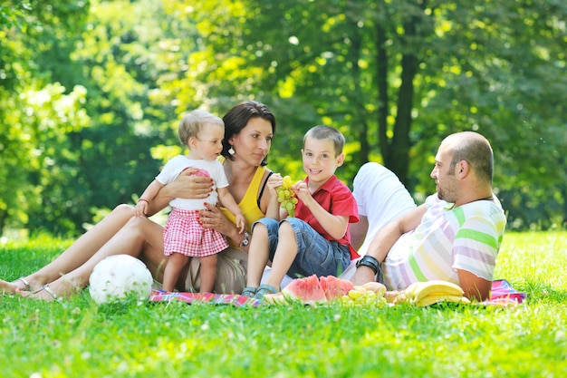 Feliz pareja joven con sus hijos se divierten en el hermoso parque al aire libre en la naturaleza