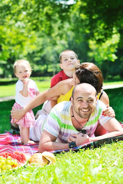 Feliz pareja joven con sus hijos se divierten en el hermoso parque al aire libre en la naturaleza