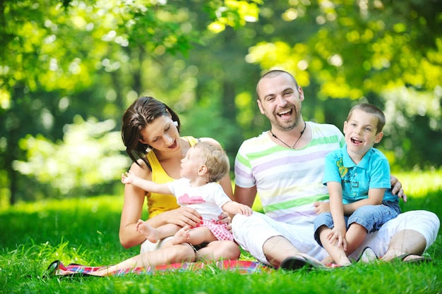 Feliz pareja joven con sus hijos se divierten en el hermoso parque al aire libre en la naturaleza