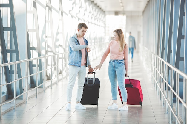 Foto feliz pareja joven en la terminal del aeropuerto divirtiéndose mientras espera su vuelo. dos personas hombre y mujer van a tropezar.