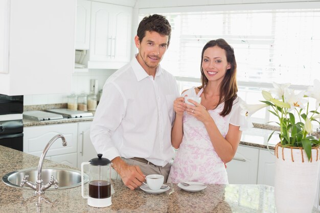 Feliz pareja joven tomando un café en la cocina