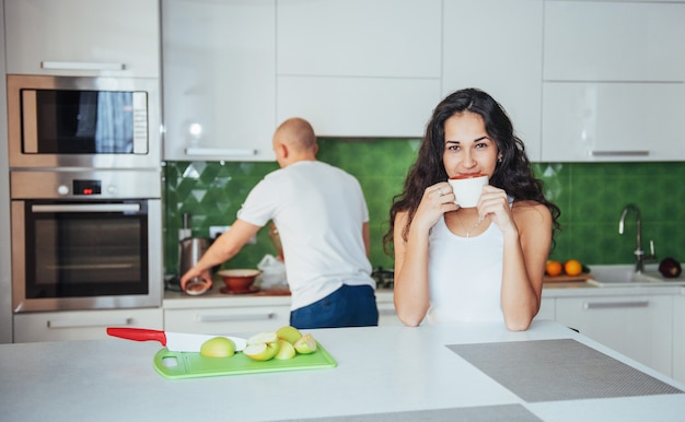 Feliz pareja joven tomando un café en la cocina