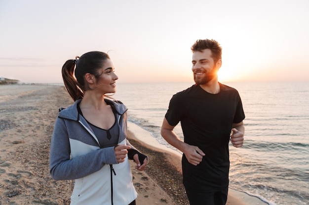 Feliz pareja joven trotar juntos en la playa