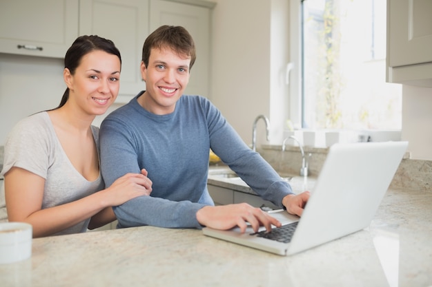 Feliz pareja joven usando laptop