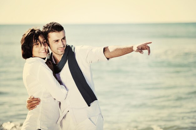 feliz pareja joven vestida de blanco tiene recreación romántica y diversión en la hermosa playa de vacaciones