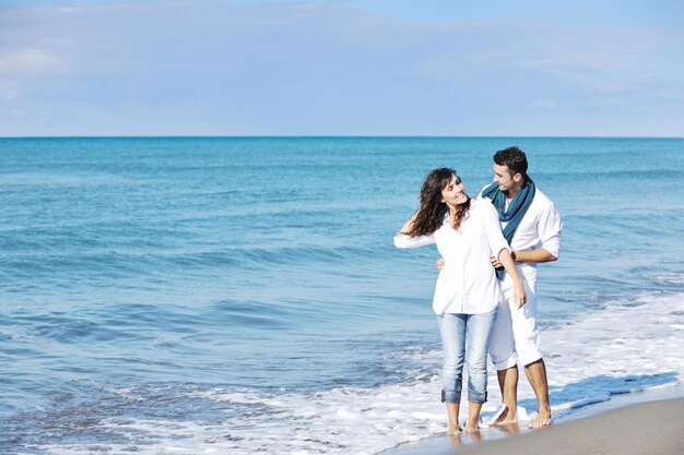 feliz pareja joven vestida de blanco tiene recreación romántica y diversión en la hermosa playa de vacaciones