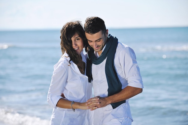 feliz pareja joven vestida de blanco tiene recreación romántica y diversión en la hermosa playa de vacaciones