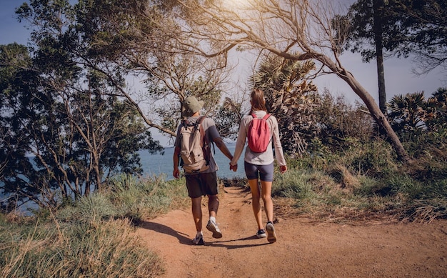 Feliz pareja joven viajando por el bosque selvático cerca del océano