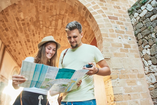 Feliz pareja joven de viajeros sosteniendo mapa en manos