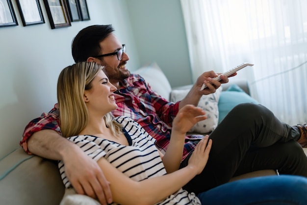 Feliz pareja joven viendo la televisión en su casa