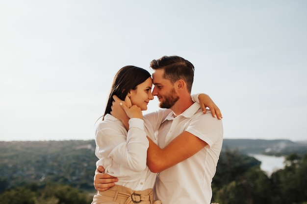 Feliz pareja de jóvenes amantes se abrazan al aire libre en un día soleado.