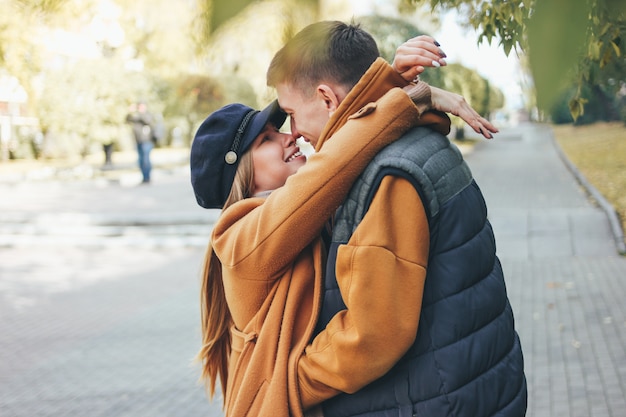 Feliz pareja de jóvenes enamorados adolescentes amigos vestidos de estilo casual caminando juntos en la calle de la ciudad en temporada fría