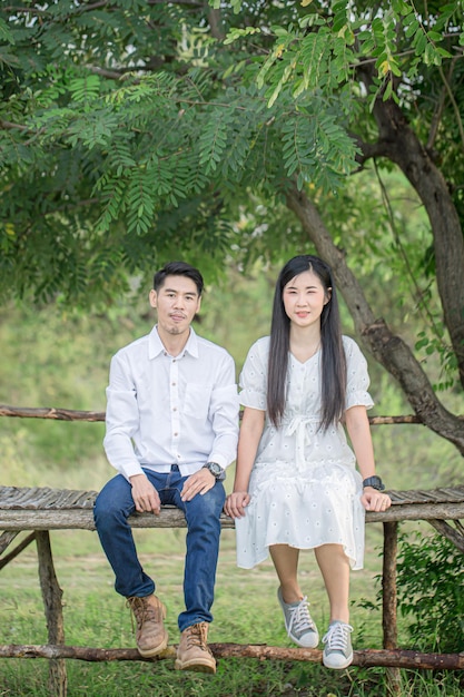 Feliz pareja de jóvenes enamorados sentados en un banco del parque y mirando a la cámara