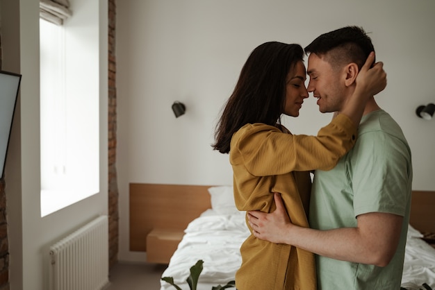 Feliz pareja de jóvenes está abrazando y mostrando sus sentimientos. Familia joven que se muda a un nuevo apartamento.