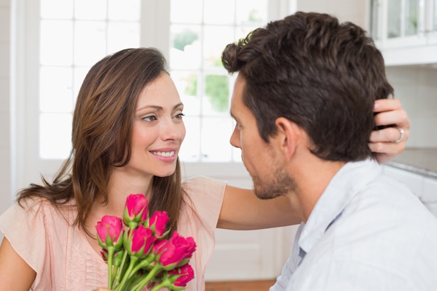 Feliz pareja de jóvenes con flores en casa