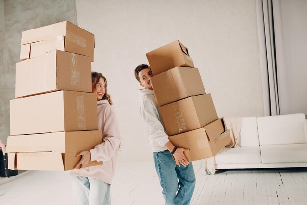 Feliz pareja de jóvenes, hombre y mujer, se mudan con cajas de cartón a un nuevo apartamento.