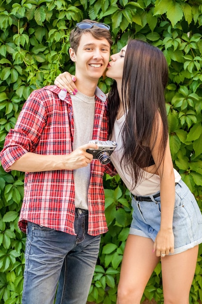 Foto una feliz pareja de jóvenes de pie contra las plantas