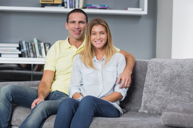 Feliz pareja de jóvenes sentados en su sofá