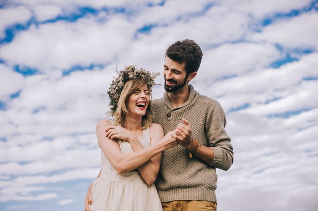 feliz pareja de jóvenes tomados de la mano contra el cielo