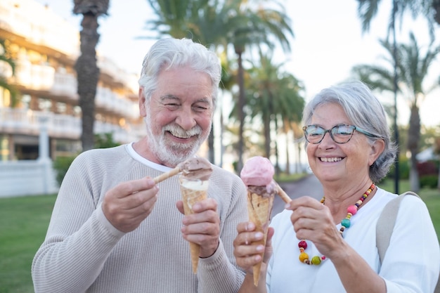 Feliz pareja de jubilados adultos divirtiéndose comiendo helado en el parque disfrutando de la jubilación divertida