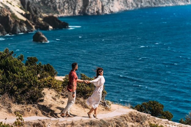 Feliz pareja junto al mar. Amantes de la luna de miel. Hombre y mujer en la isla. Hermosa pareja divirtiéndose junto al mar. Feliz pareja de vacaciones. Hombre y mujer junto al mar. Sígueme. Copia espacio