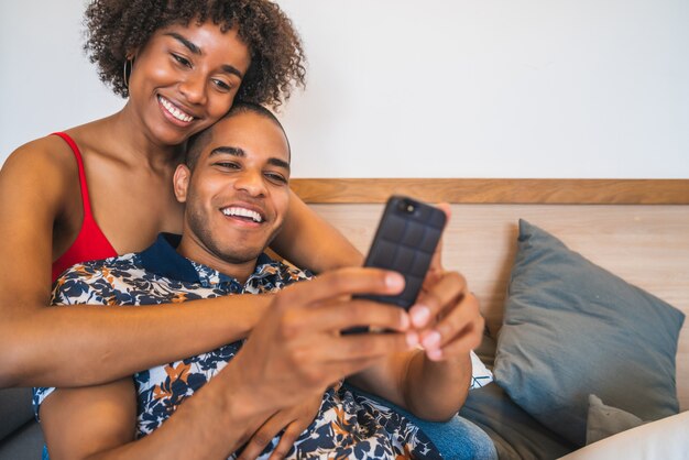 Feliz pareja latina tomando un selfie con teléfono en casa