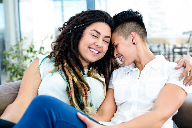 Feliz pareja de lesbianas descansando en el sofá en la sala de estar