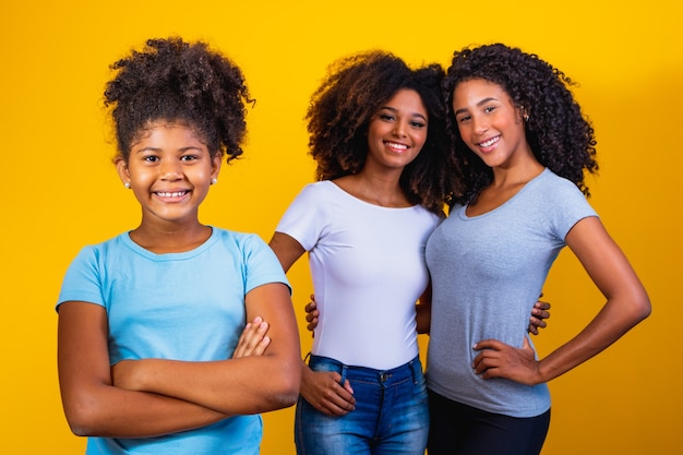 Feliz pareja de lesbianas con niño sobre fondo amarillo. Pareja junto con hija adoptiva, concepto de adopción