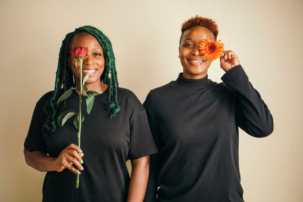 Feliz pareja de lesbianas de pie con flores