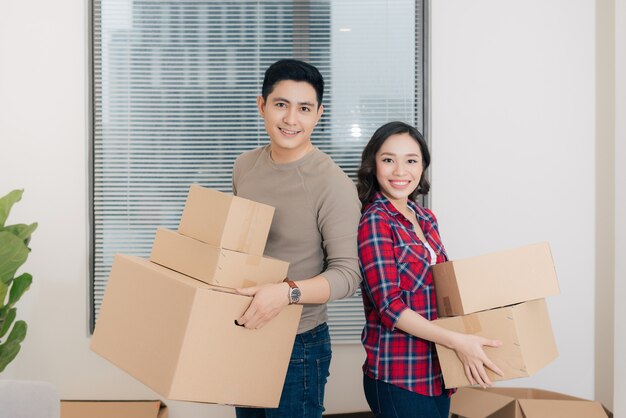 Feliz pareja llevando cajas en su nueva casa. Mudarse de casa.